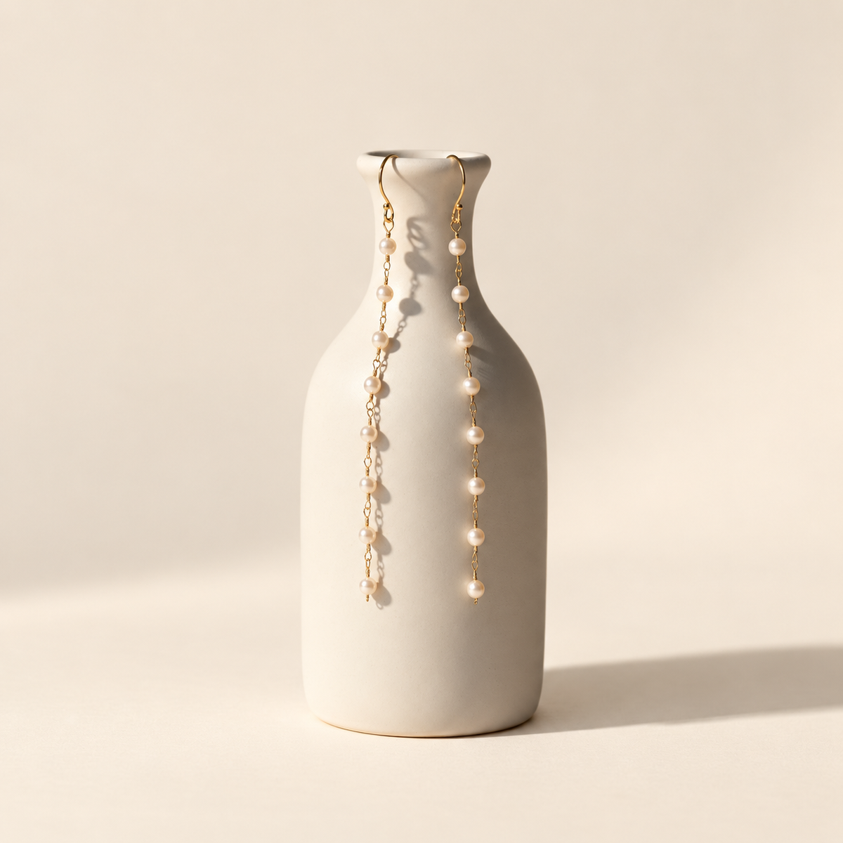 Eliane Pearl Linear Drop Earrings on warm ivory-beige background