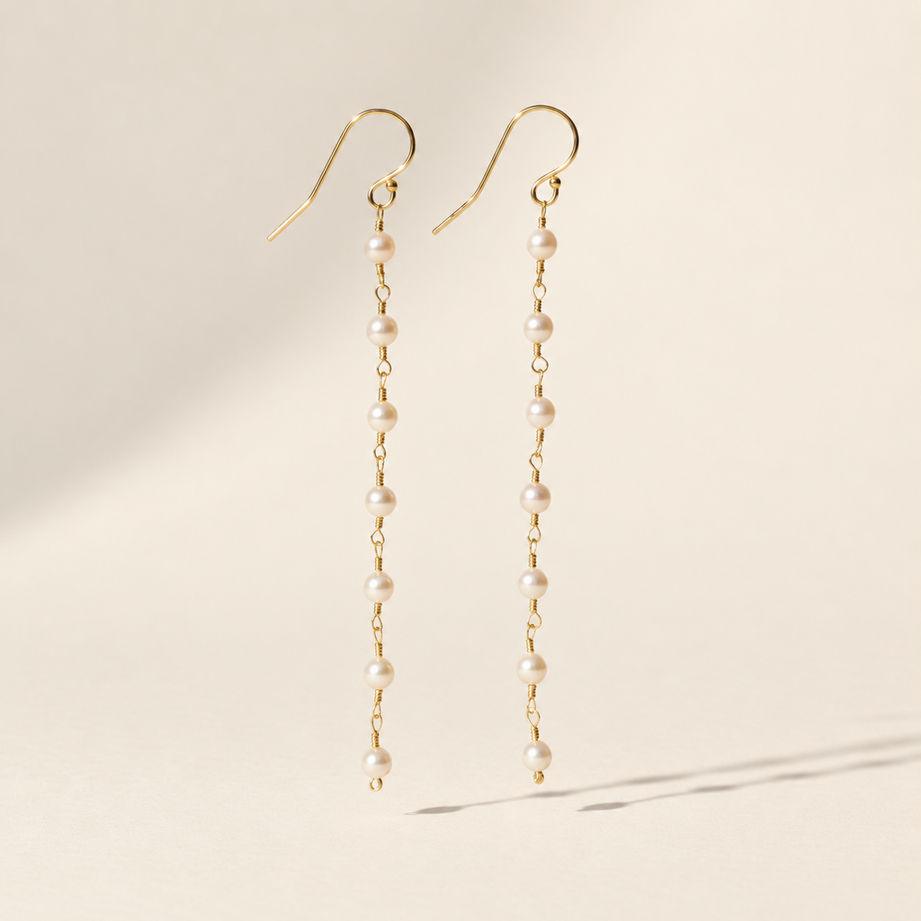 Eliane Pearl Linear Drop Earrings on warm ivory-beige background