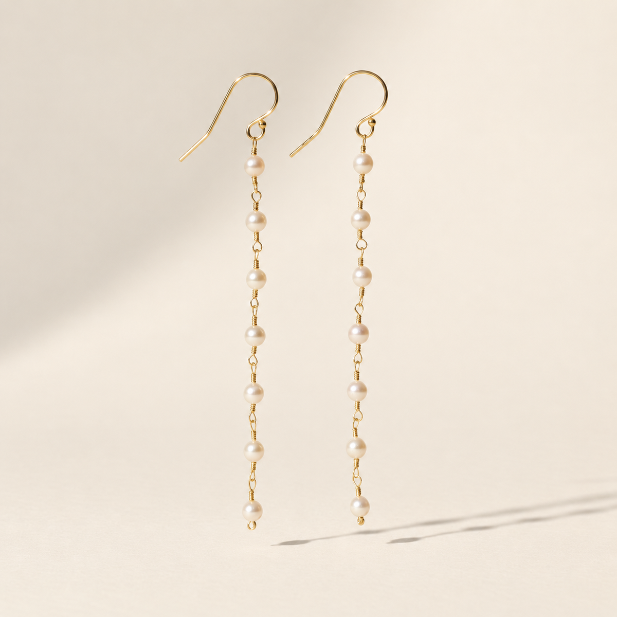 Eliane Pearl Linear Drop Earrings on warm ivory-beige background